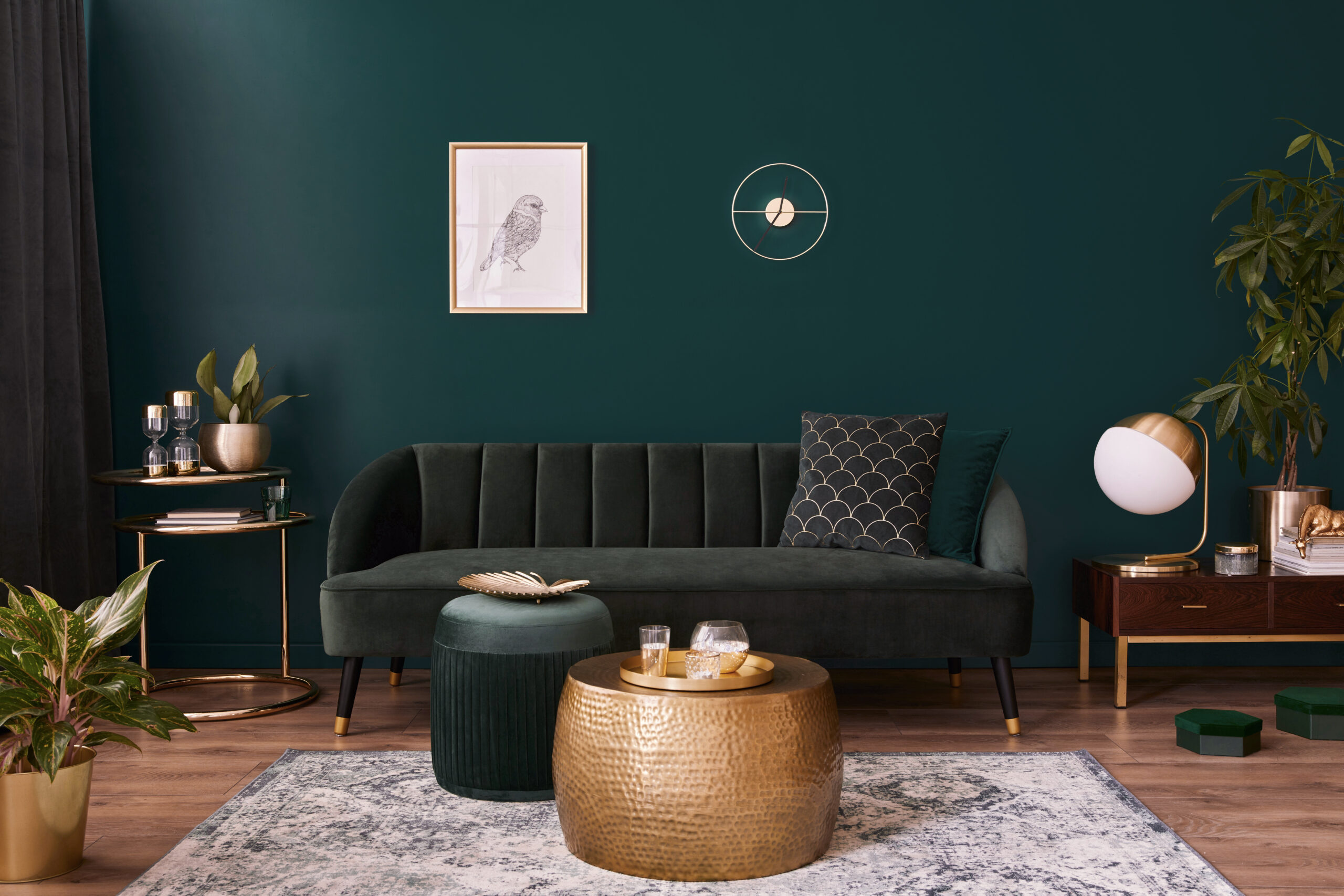 Luxury living room in house with modern interior design, green velvet sofa, coffee table, pouf, gold decoration, plant, lamp, carpet, mock up poster frame and elegant accessories. Template.
